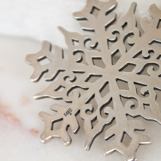 Silver snowflake pendant on a marble surface