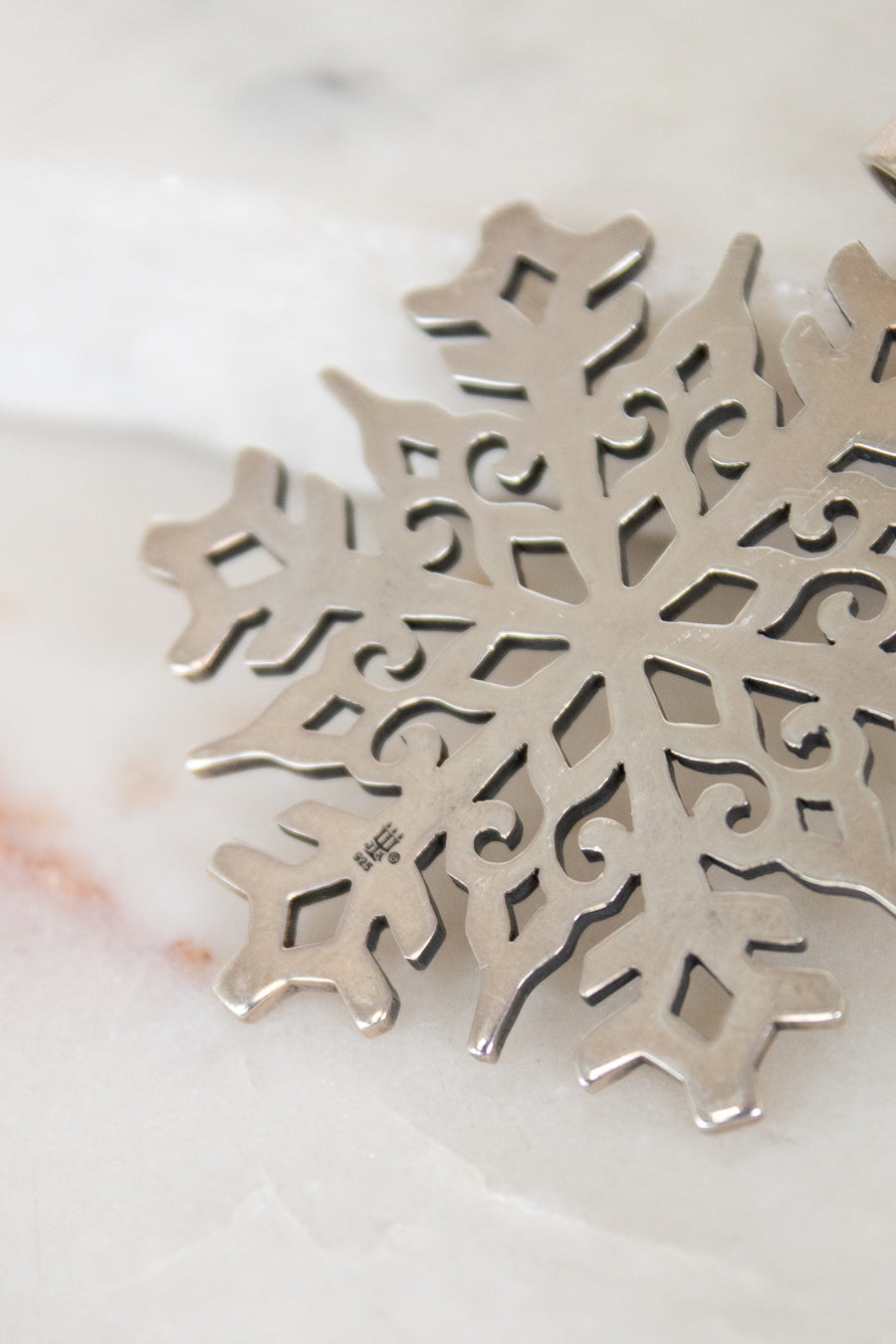 Silver snowflake pendant on a marble surface