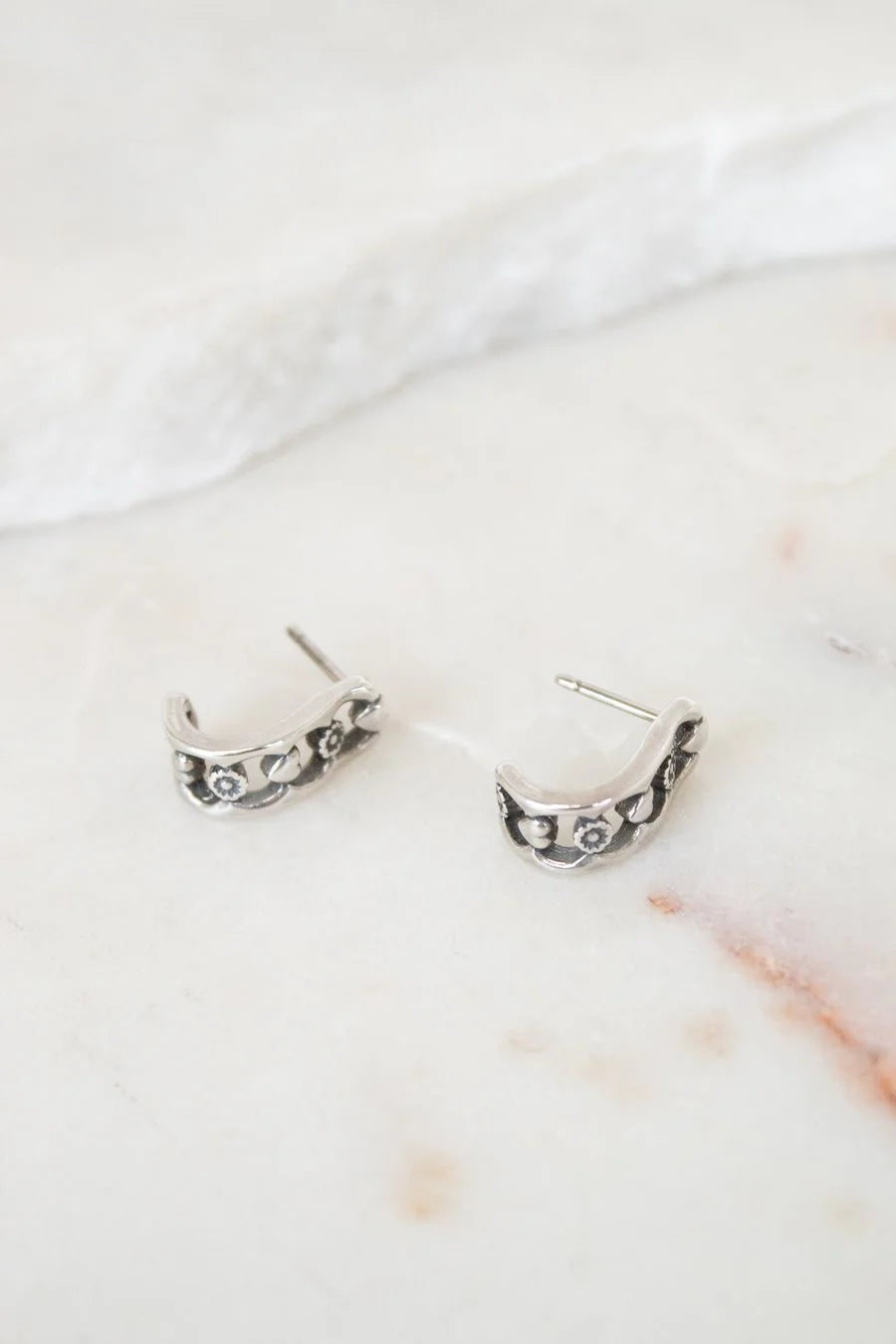 Pair of silver hoop earrings on a marble surface