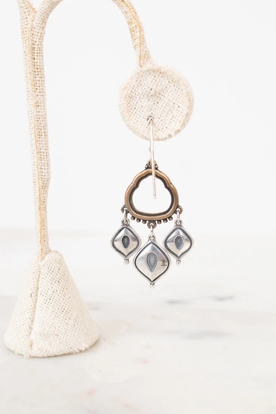 Back view of bronze and silver earrings on a white background