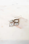Pair of silver earrings with teardrop-shaped charms on a marble surface