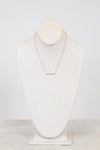 Gold necklace on a white mannequin bust against a white background