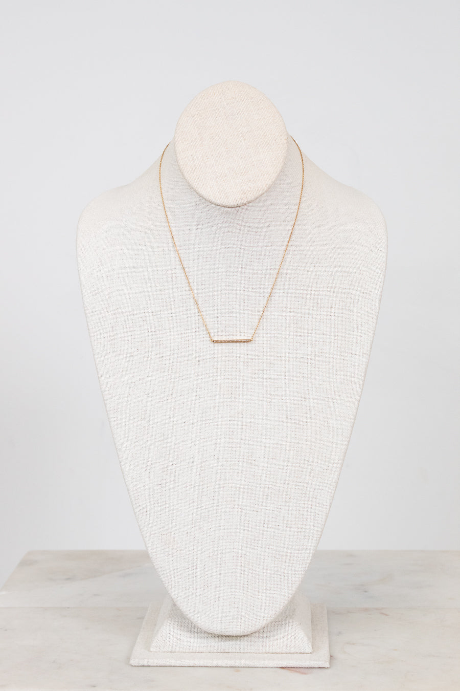 Gold necklace on a white mannequin bust against a white background