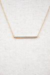 Gold necklace with a bar pendant on a light gray background