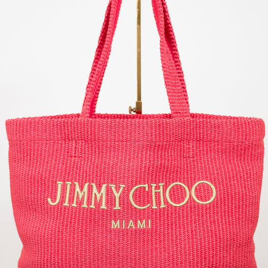 Pink tote bag with 'Jimmy Choo Miami' text on a white background