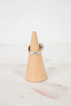 Silver ring on a wooden cone against a marble background