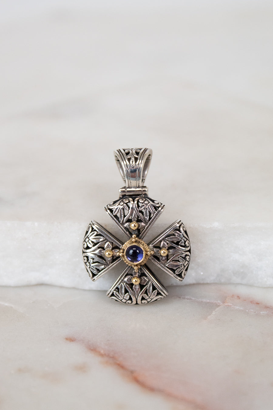 Silver and gold cross pendant on white background