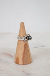 Silver ring with a black stone on a wooden cone against a light background