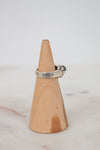 Silver ring on a wooden cone against a light background