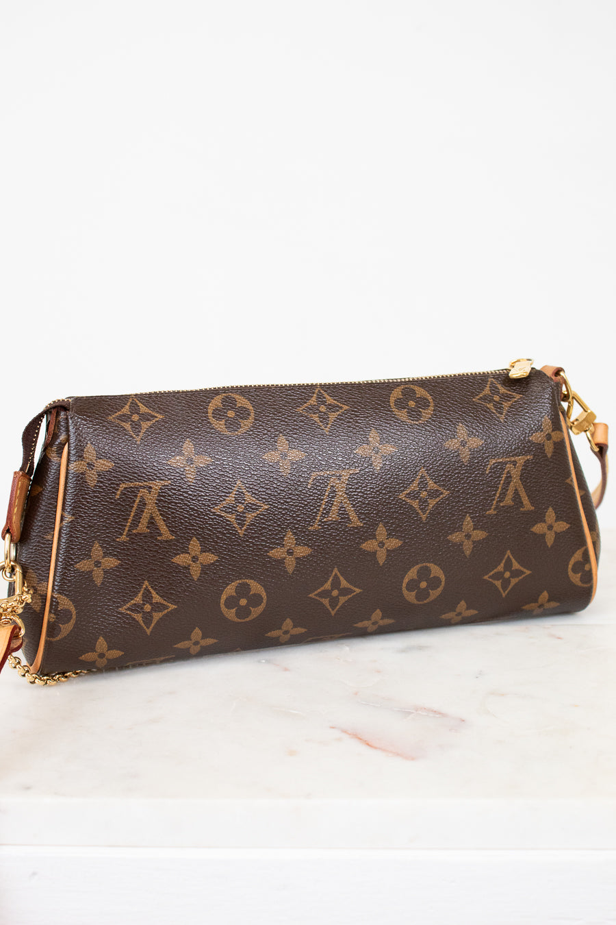 Brown handbag with gold monogram pattern on a white surface