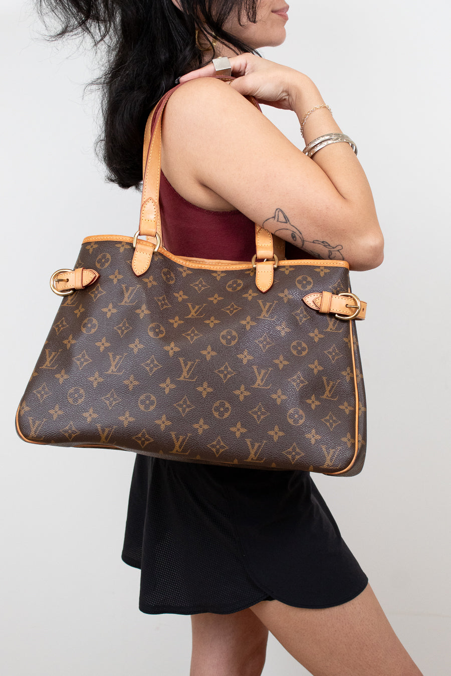 Person holding a Louis Vuitton handbag against a plain background