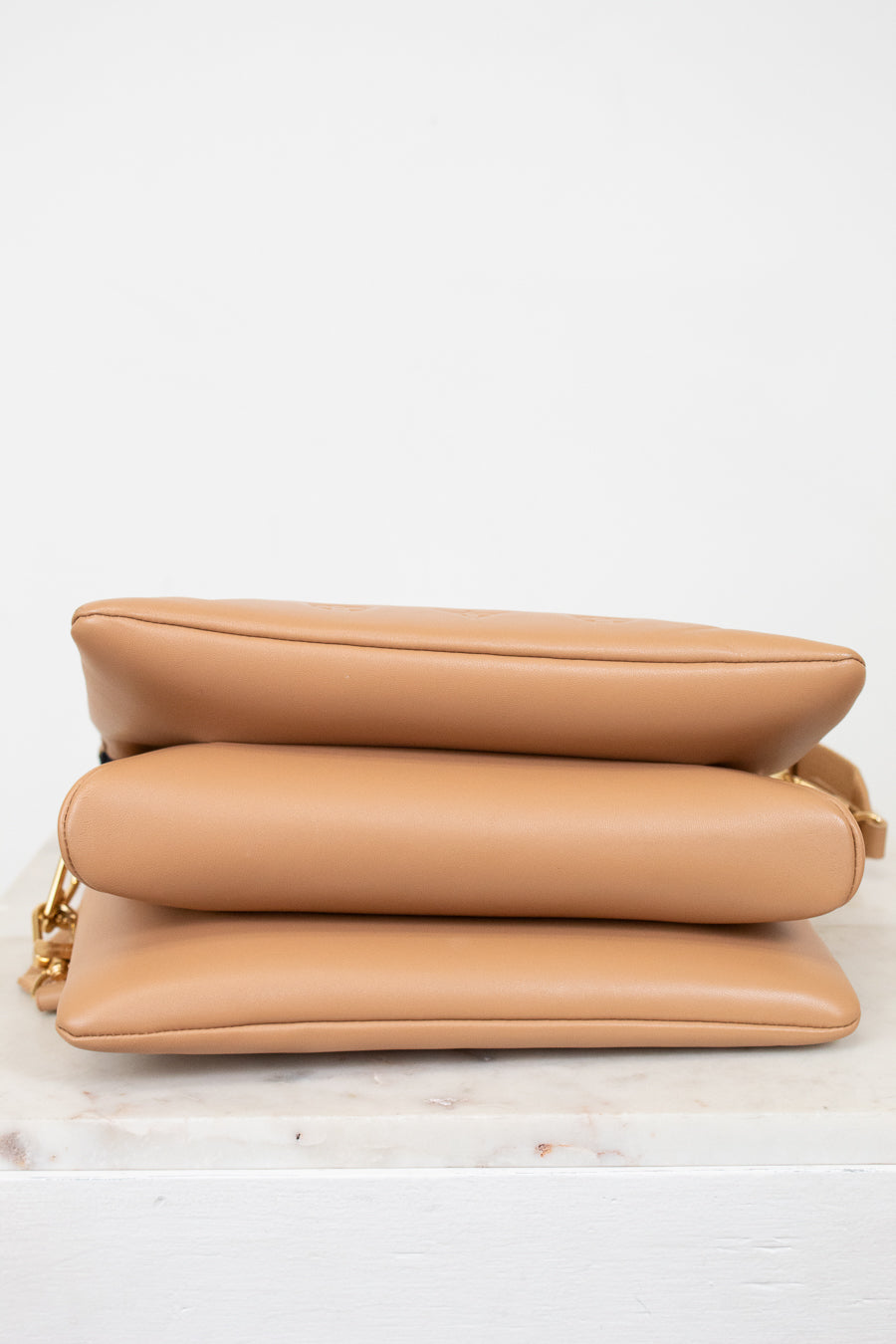 Tan handbag on a light surface with a white background