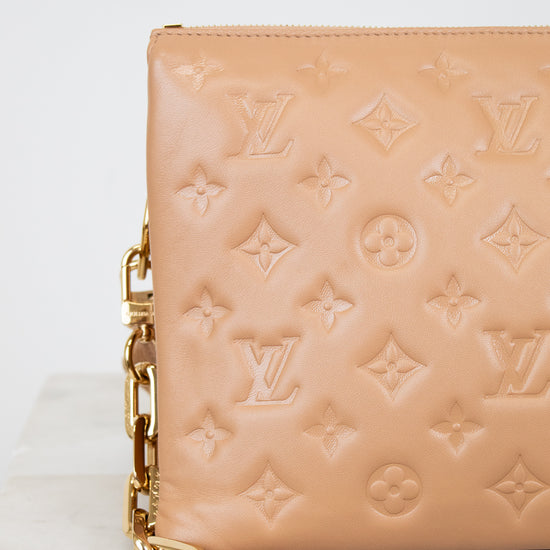 Beige handbag with gold chain detail on a marble surface