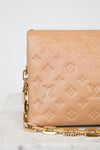 Beige handbag with gold chain detail on a marble surface