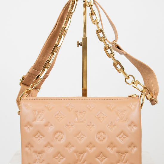 Beige handbag with gold chain strap on a white background
