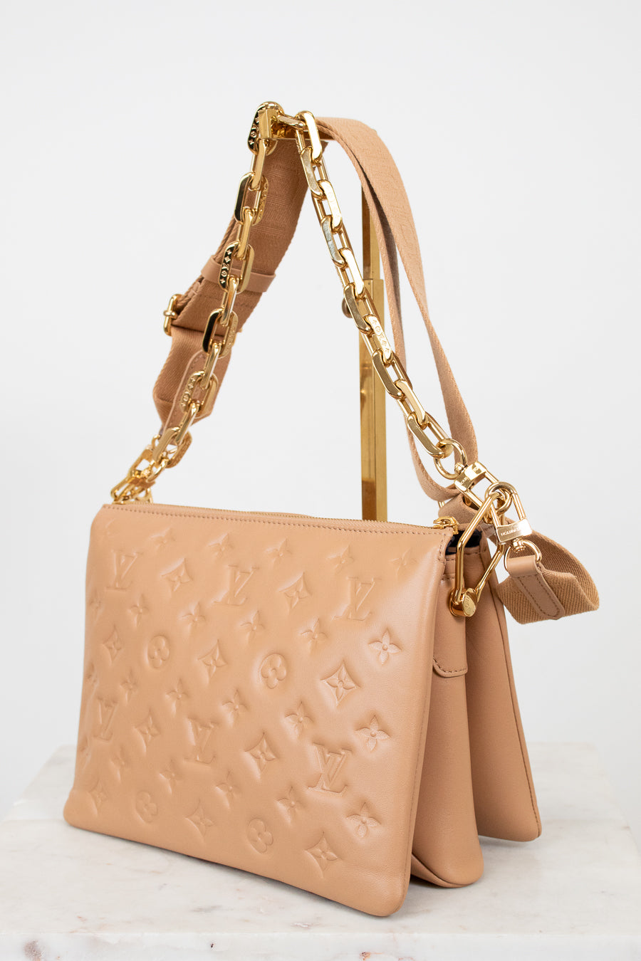 Beige handbag with gold chain strap on a light background