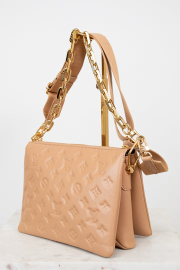 Beige handbag with gold chain strap on a light background