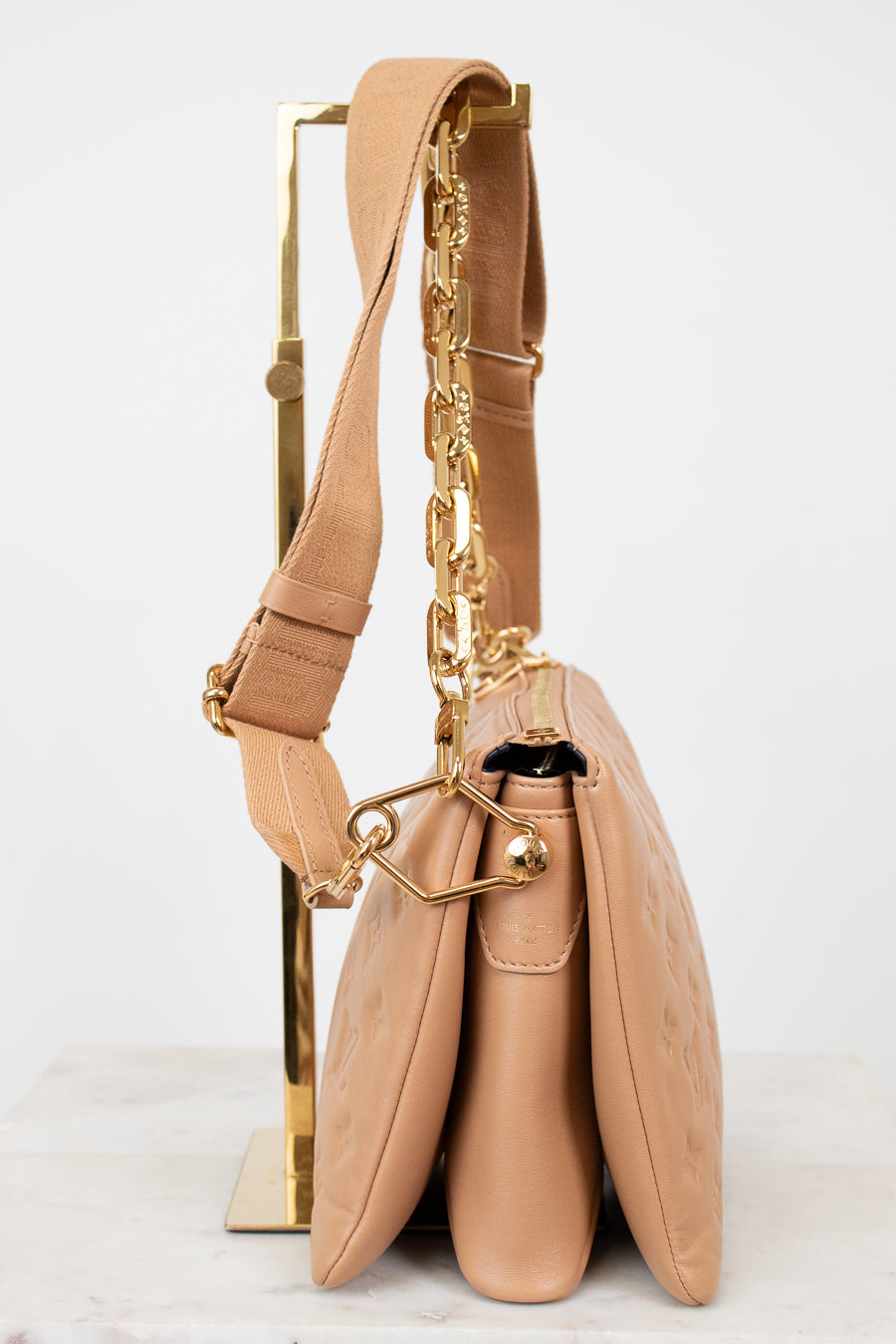 Beige handbag with gold chain detail on a white background