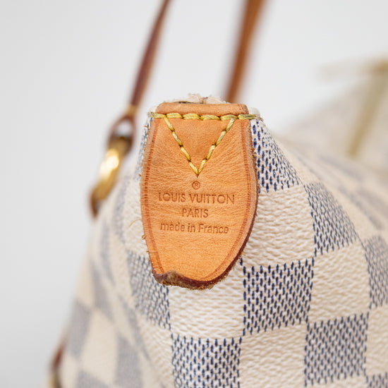 Louis Vuitton handbag with checkered pattern and brown leather tag.