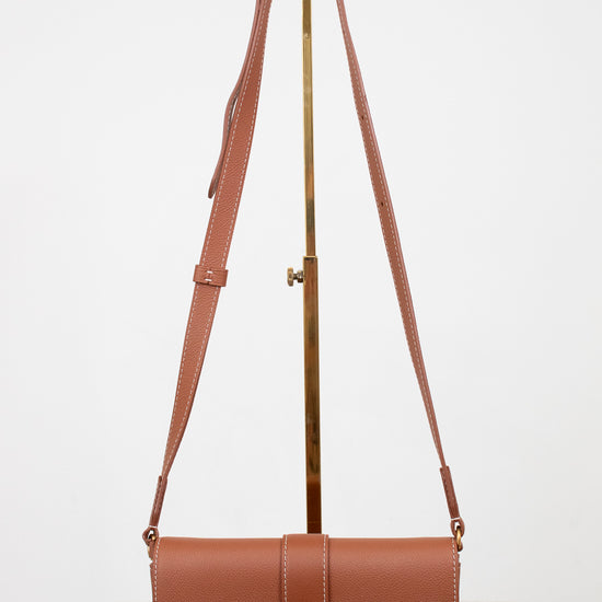 Brown leather handbag with a strap on a white background