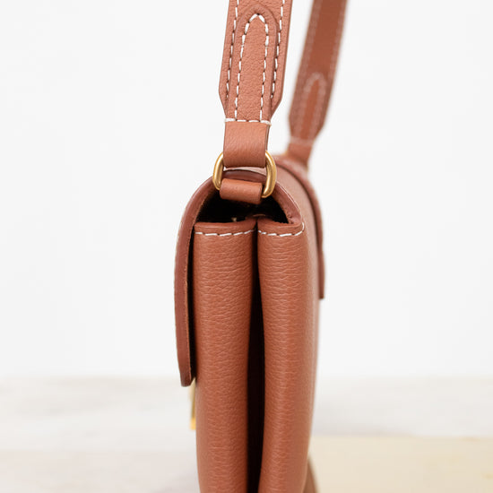 Brown leather handbag with a strap on a white background