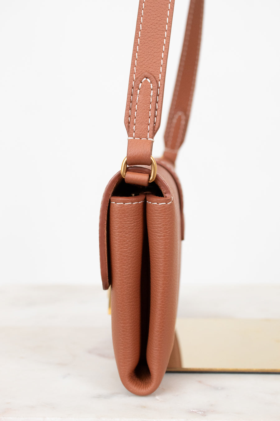 Brown leather handbag with a strap on a white background