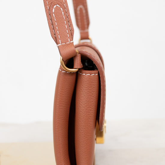 Brown leather handbag with a strap on a white background