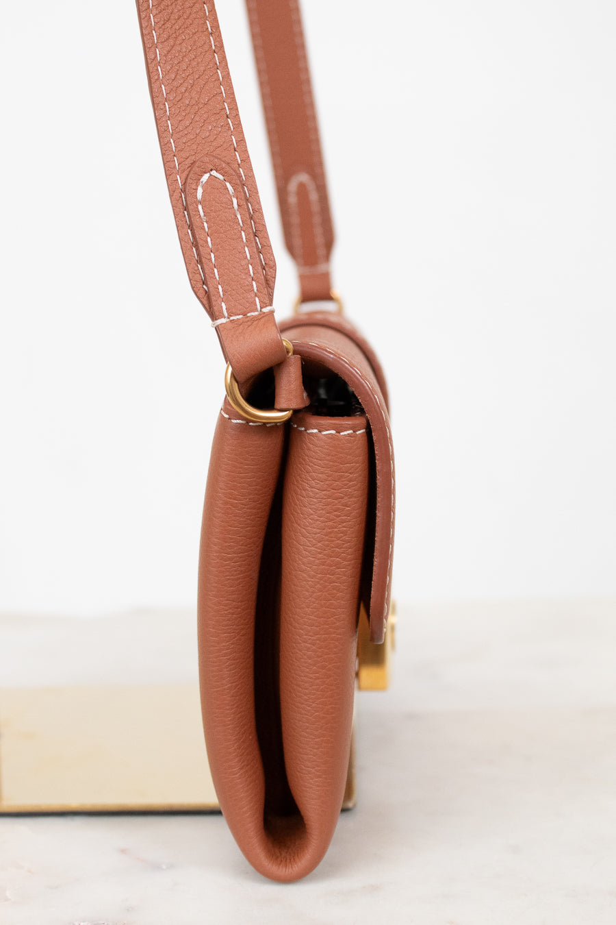 Brown leather handbag with a strap on a white background