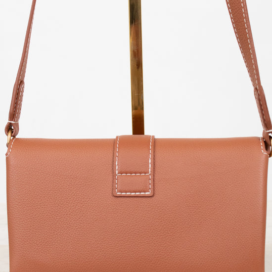 Brown leather handbag with a strap on a white background