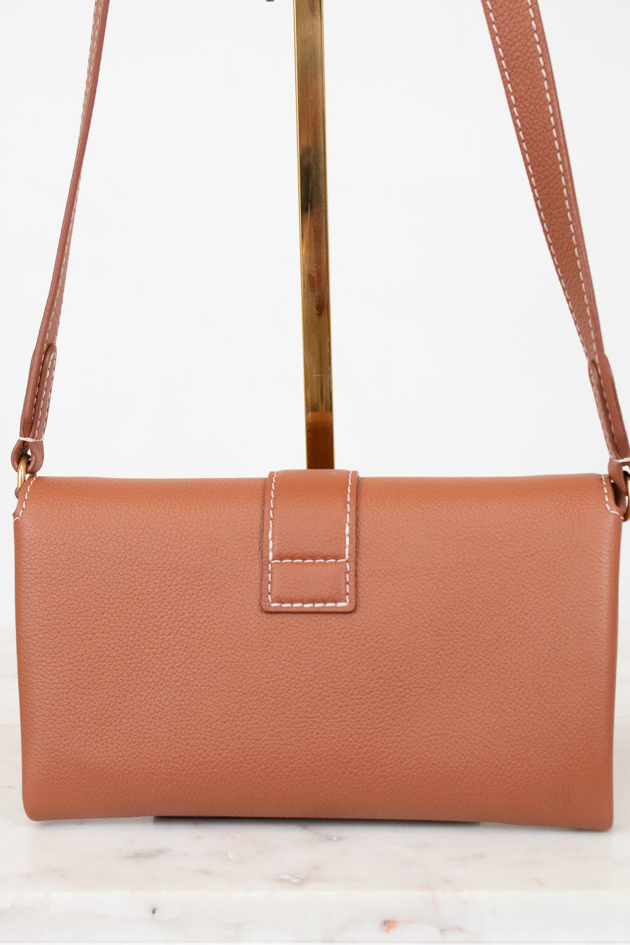 Brown leather handbag with a strap on a white background