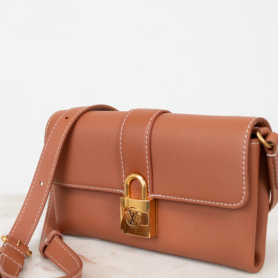 Brown handbag with gold lock on a light background