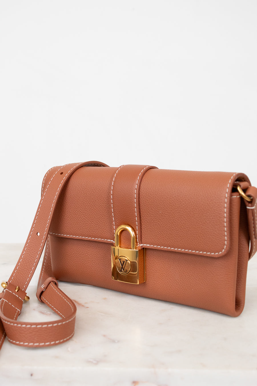 Brown handbag with gold lock on a light background