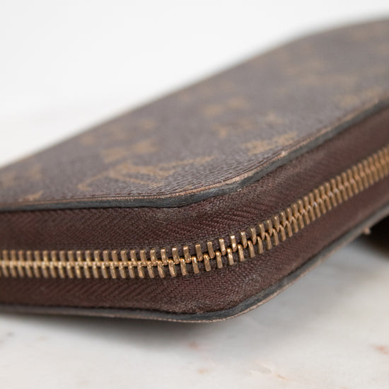 Brown leather wallet with gold zipper on a light marble background