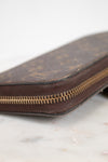 Brown leather wallet with gold zipper on a light marble background