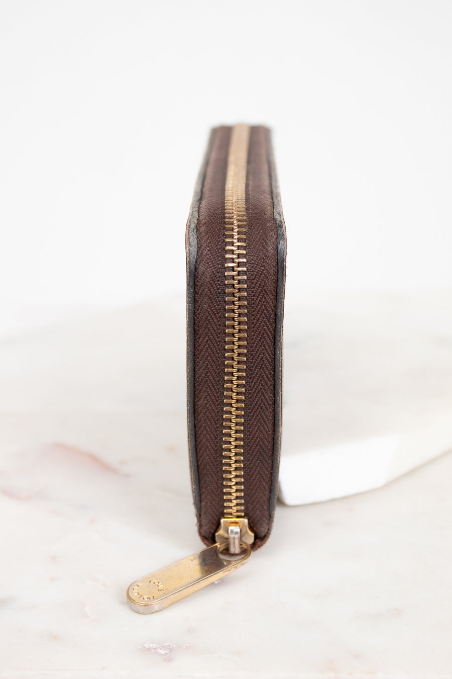 Brown wallet with gold zipper on a white background