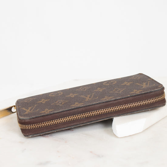 Brown wallet with gold zipper on a white marble surface