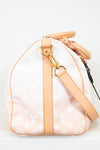 Side view of beige duffle bag with tan leather trim on white background