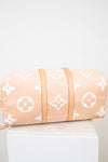 Bottom view of beige duffle bag with white monogram pattern on a light gray background