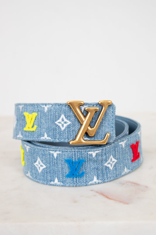 Louis Vuitton denim belt with gold buckle and mixed color monogram on white background