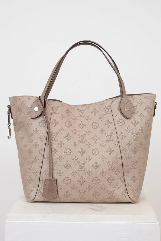Beige handbag with monogram pattern on a white background