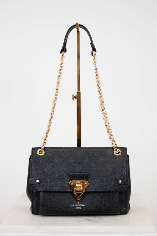 Black handbag with gold chain and hardware on a white background