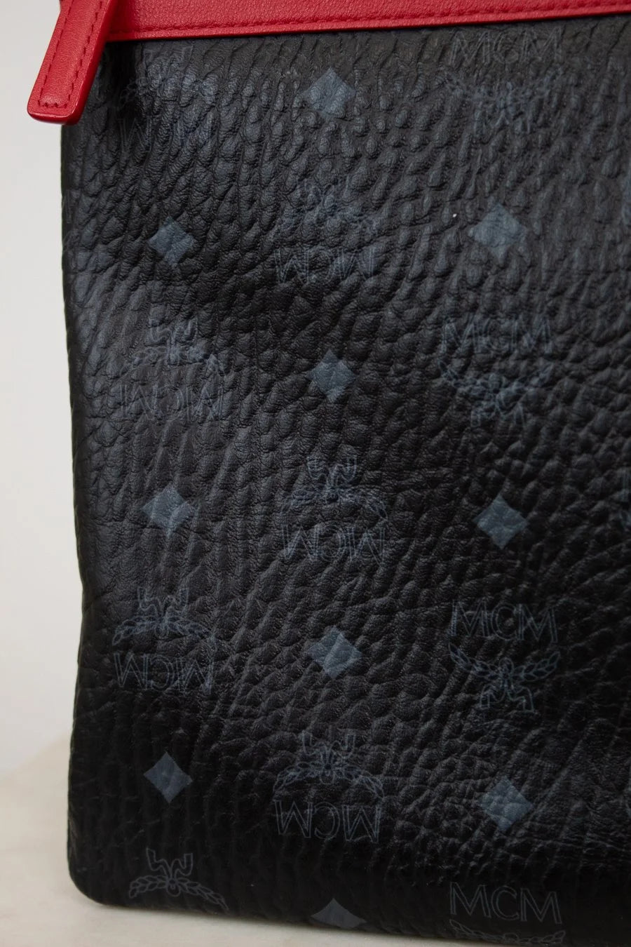 Close-up of a black textured pouch with a red border on a white background