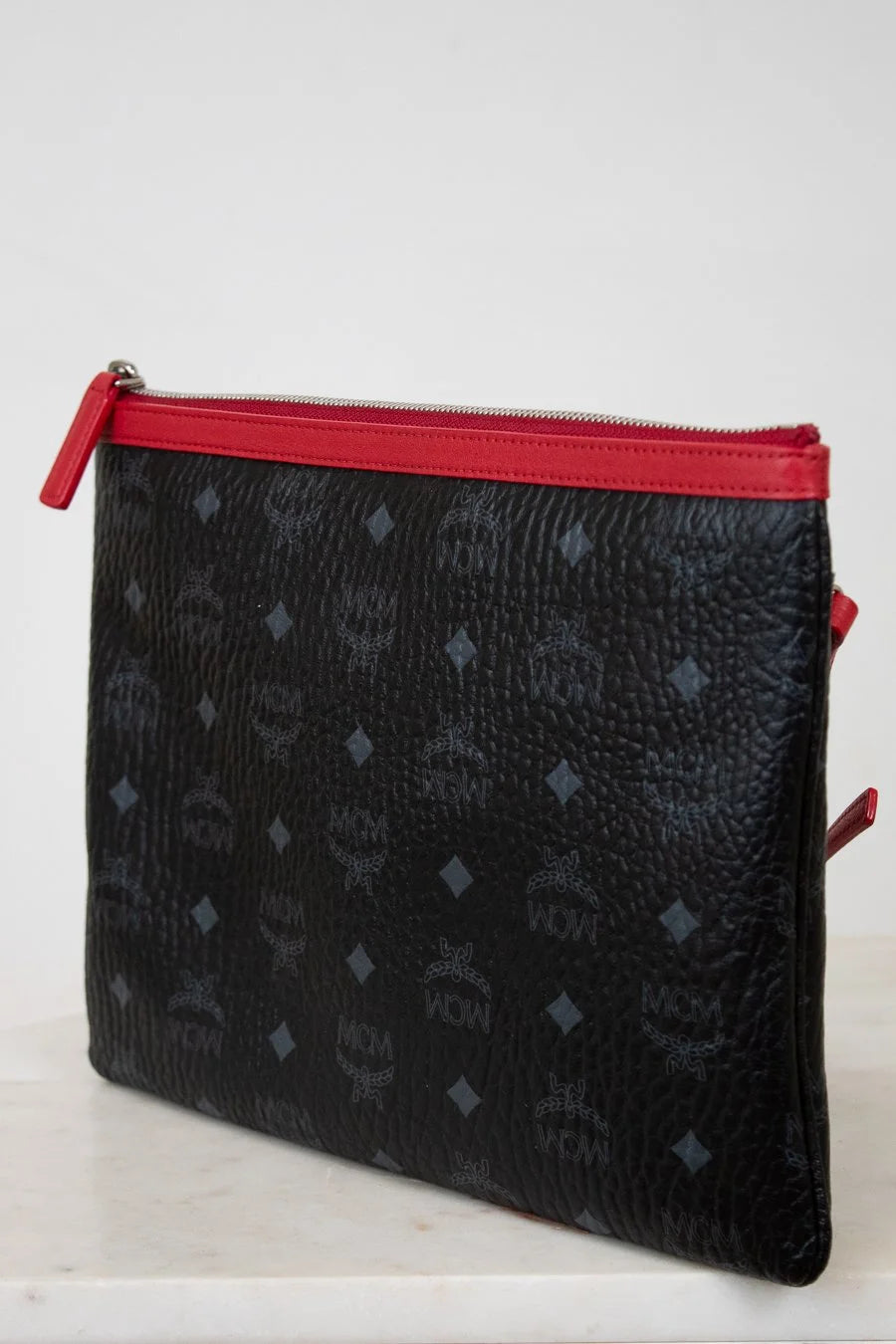Black textured pouch with red zipper on a white background