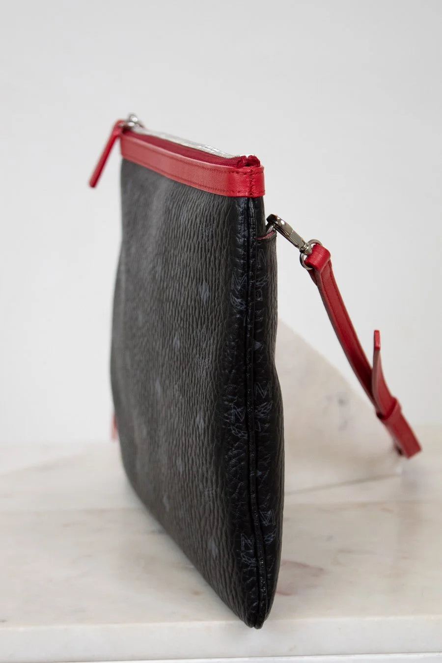 Black clutch bag with red accents on a white surface