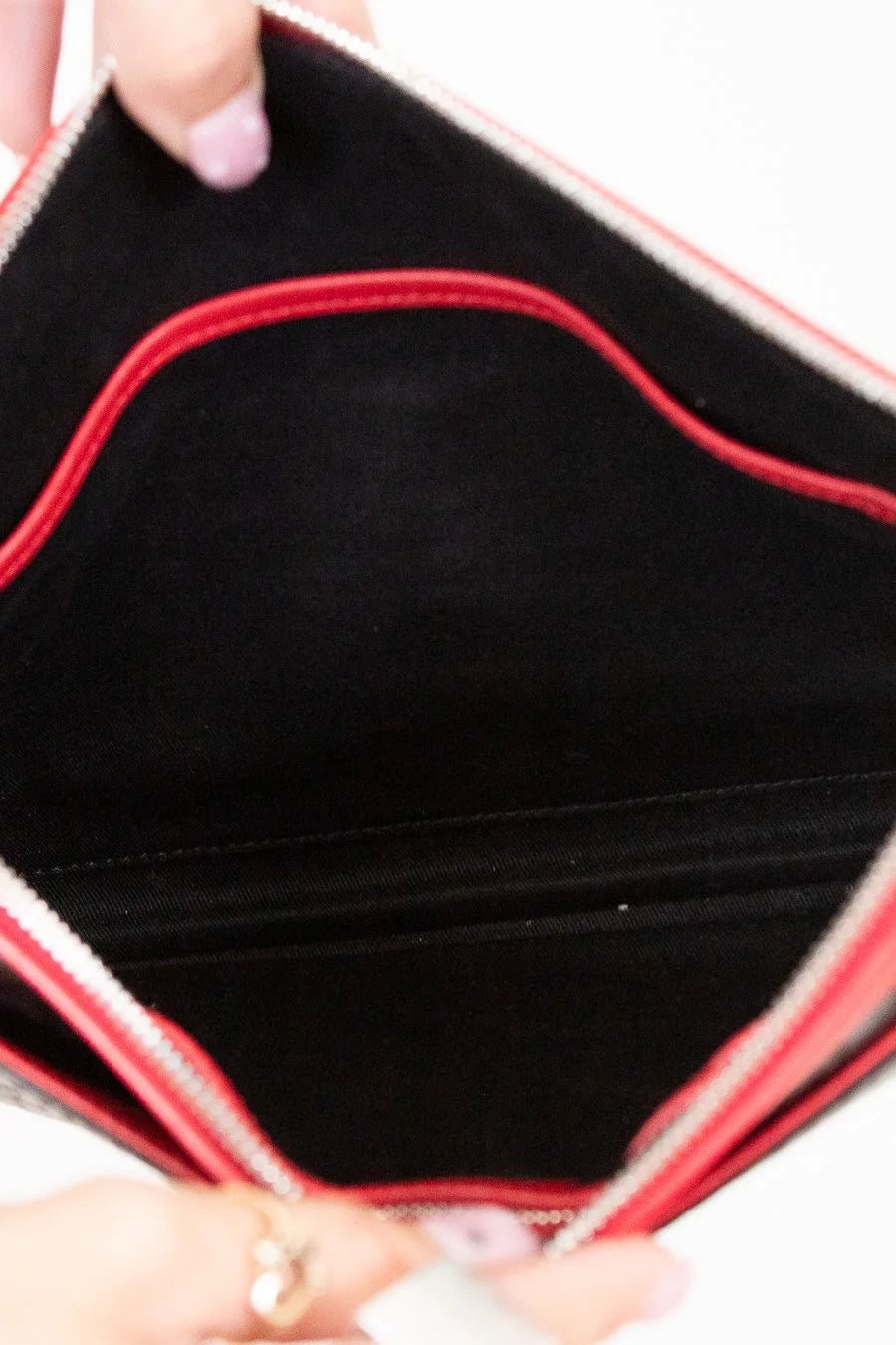 Close-up of a purse's black interior with red stitching held by a hand.