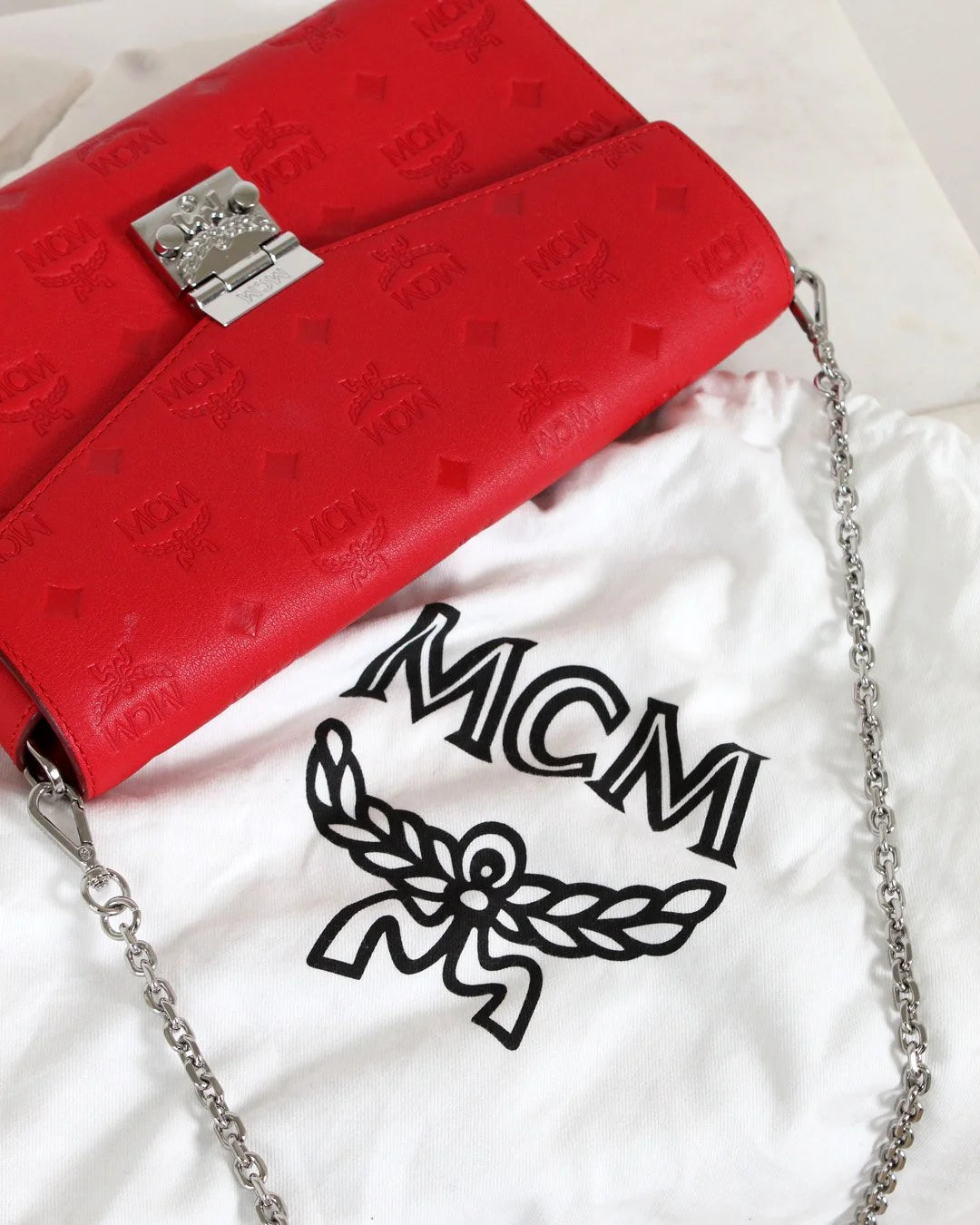 Red handbag with silver chain and MCM logo on a white background
