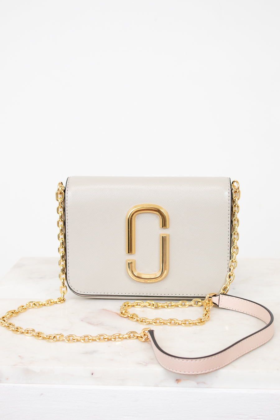 White handbag with gold chain and logo on a white background
