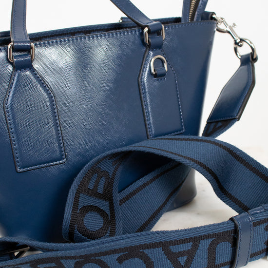 Blue handbag with a visible brand logo on the strap against a white background