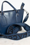 Blue handbag with a visible brand logo on the strap against a white background