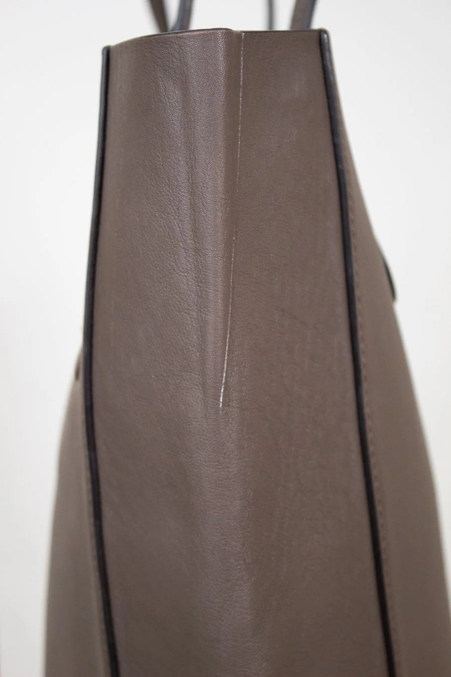 Side view of brown leather tote on white background